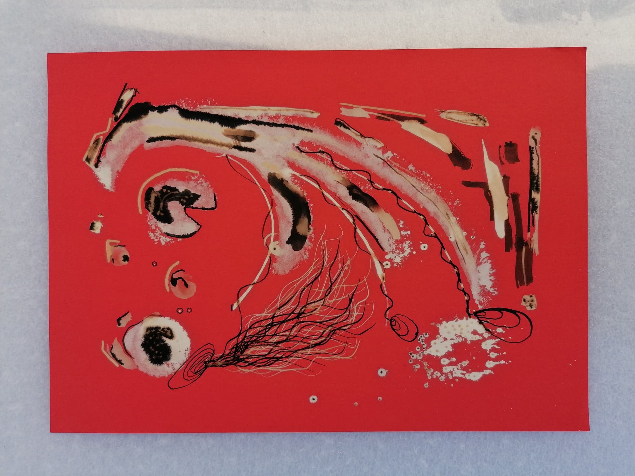 A red card with a long cream arc sweeping across it, a dark-centred eye at the lower left and fine filaments trailing beneath