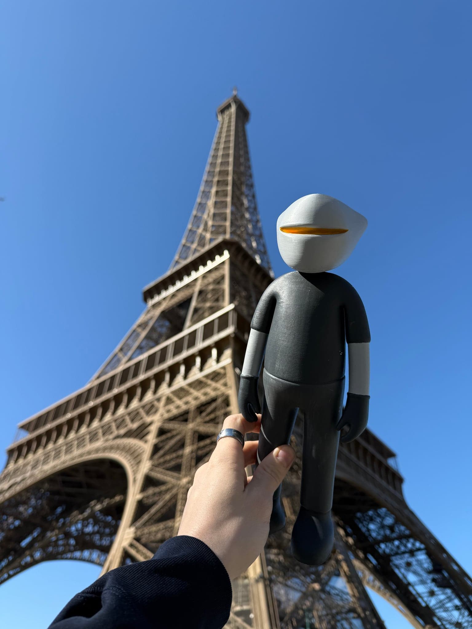 Mr. B lifted up beneath the Eiffel Tower, the ironwork rising above him