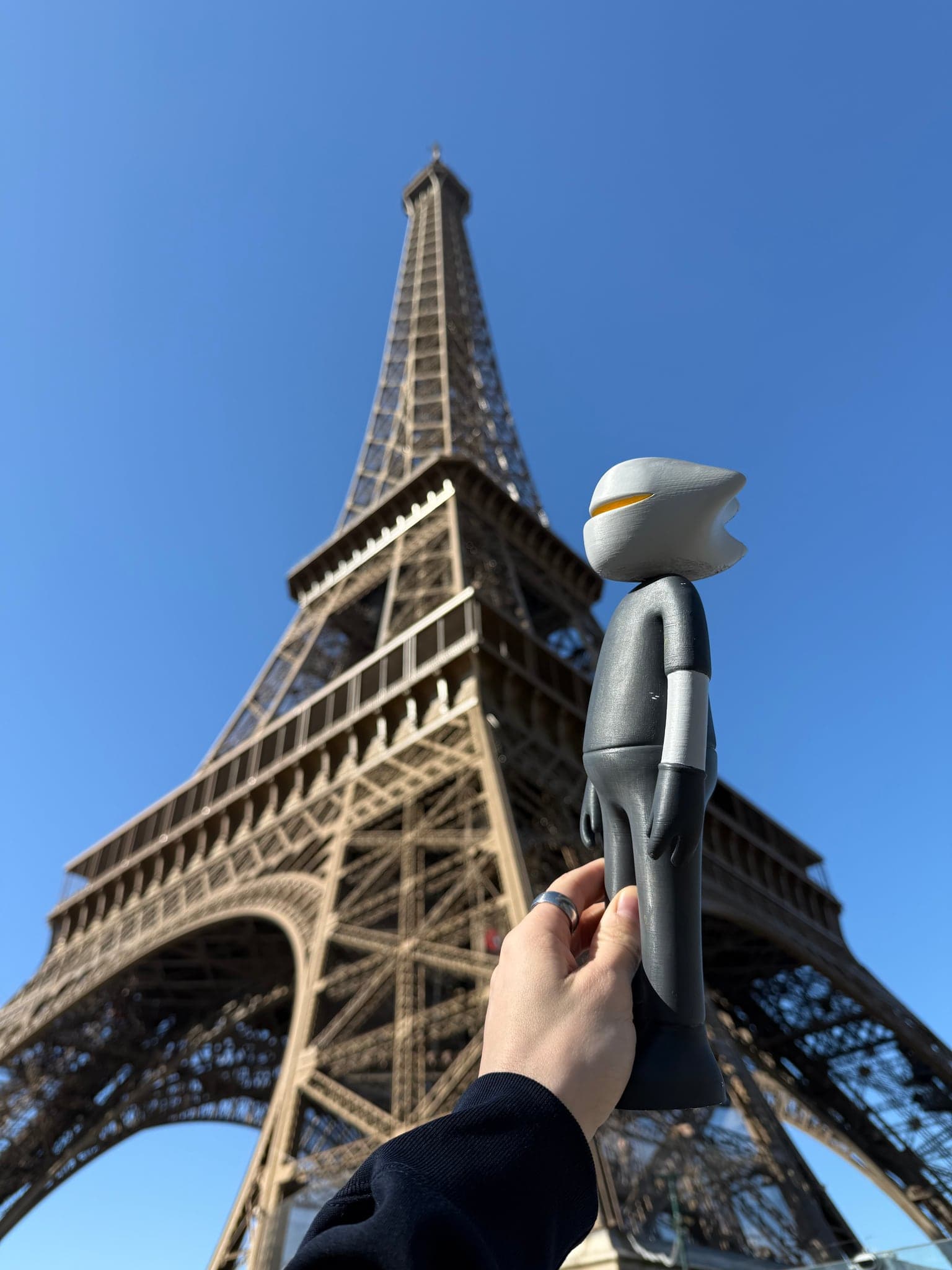 Mr. B raised into the open arch of the Eiffel Tower against blue sky