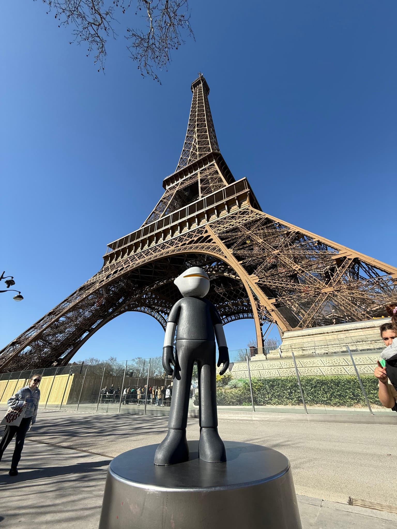 Mr. B standing unaided on a metal bollard, the Eiffel Tower filling the sky behind him