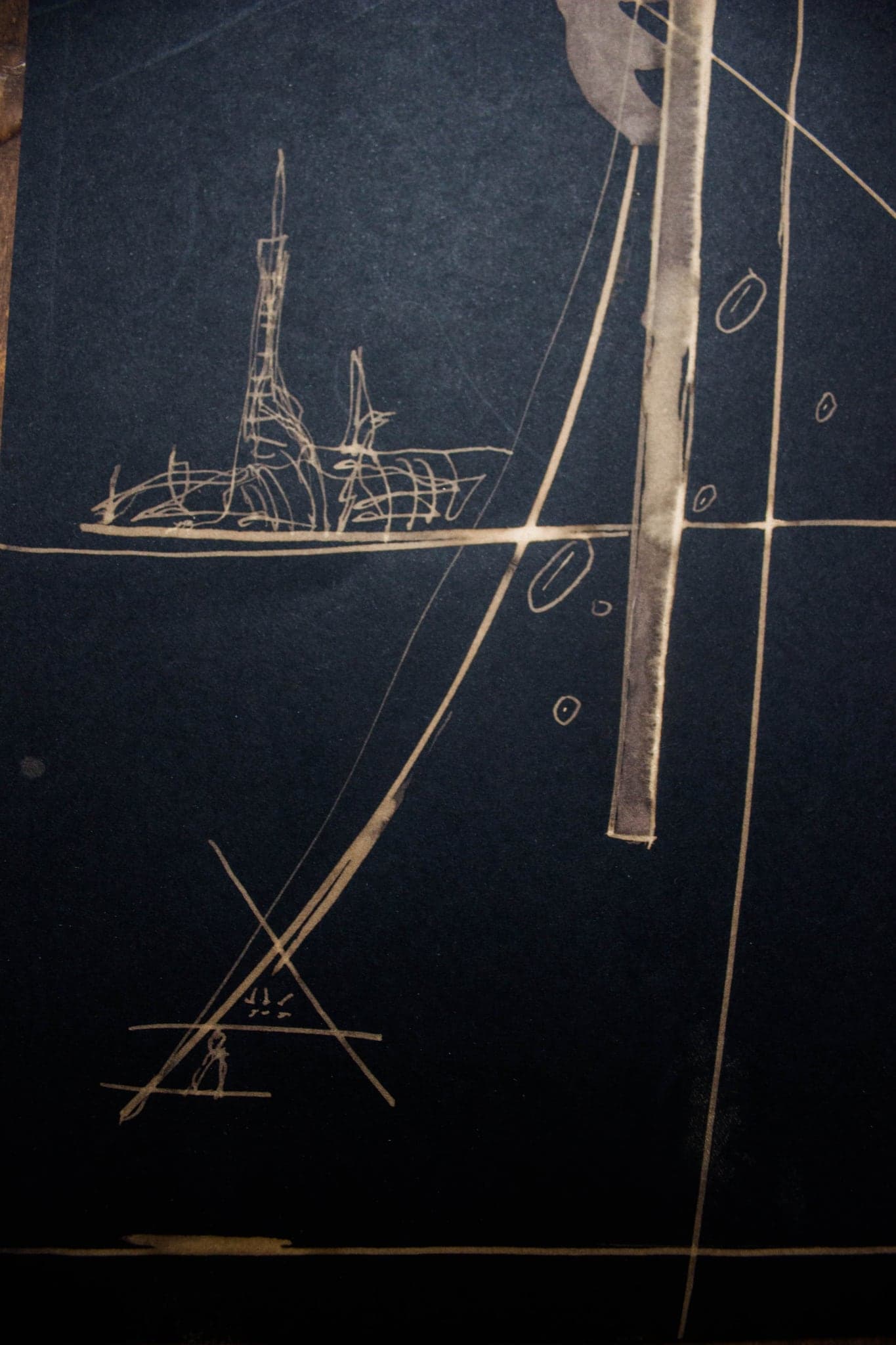 A tall sheet with a mast, a cross and a small structure low on the ground.