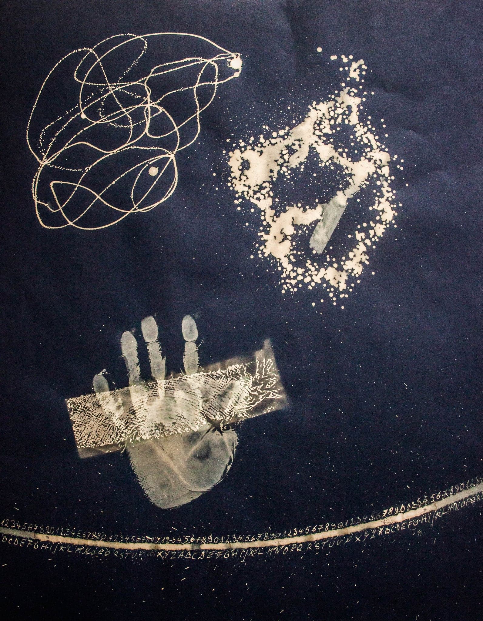 A scribbled ring, an open hand and a horizontal bar, drawn in gold.