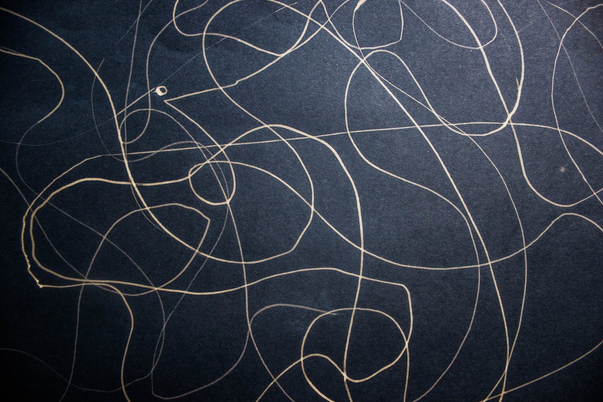 Loose pale loops running the width of a blue sheet, drawn in one unbroken movement.