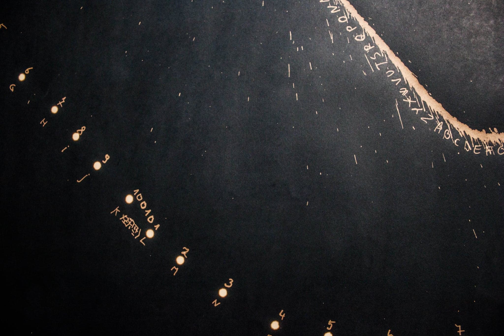 A beaded line curving down across a dark sheet, each bead a separate small mark.