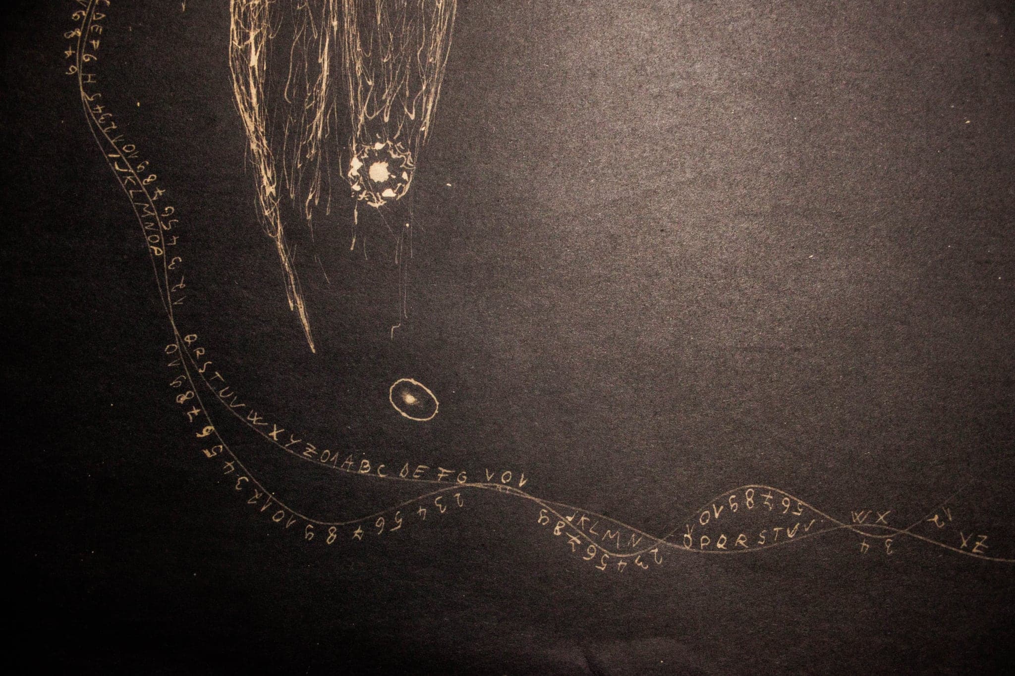 A beaded line curving across the dark, a small burst of light caught above it.