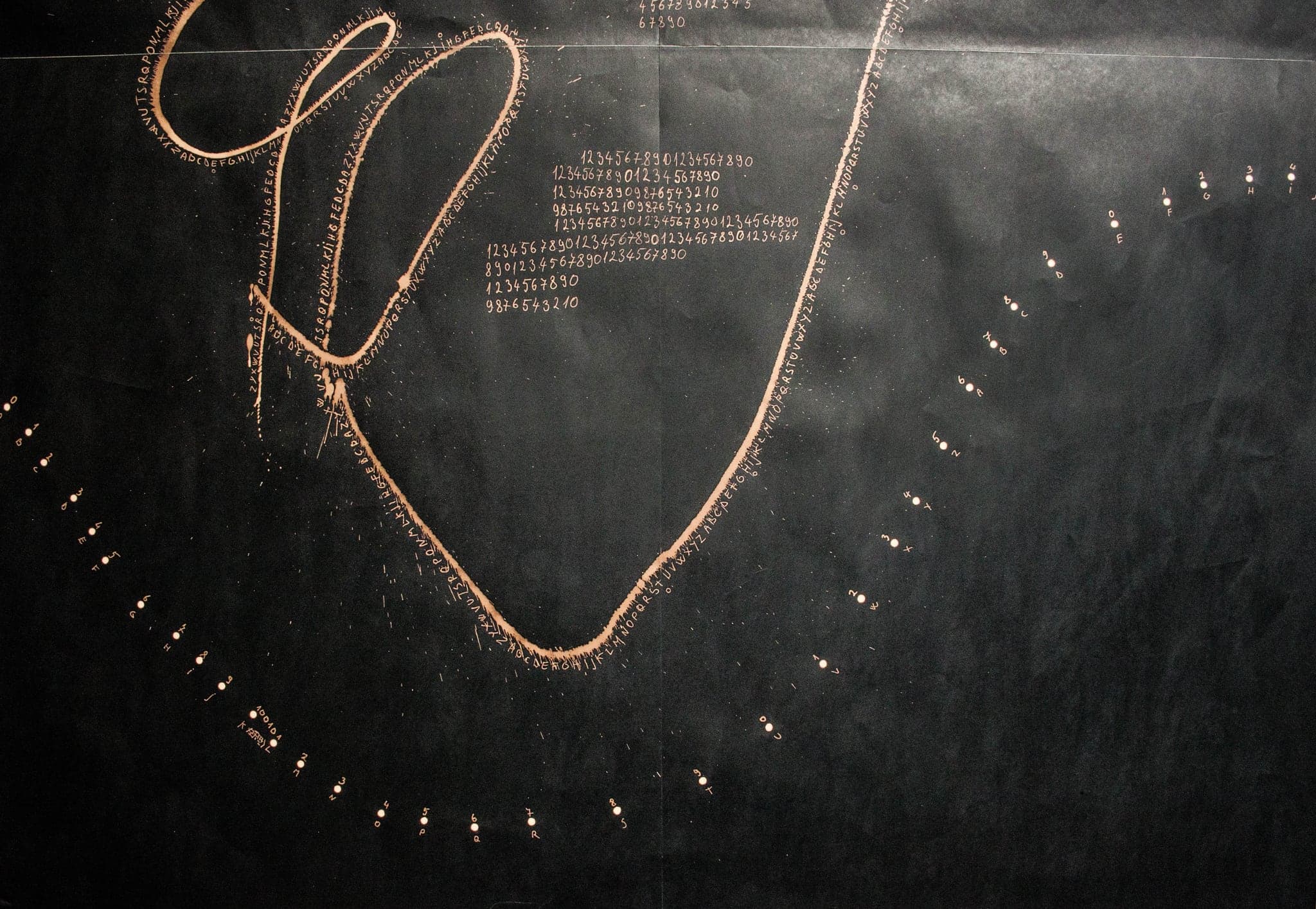 A gold loop over a beaded arc, with a block of small writing beside it.
