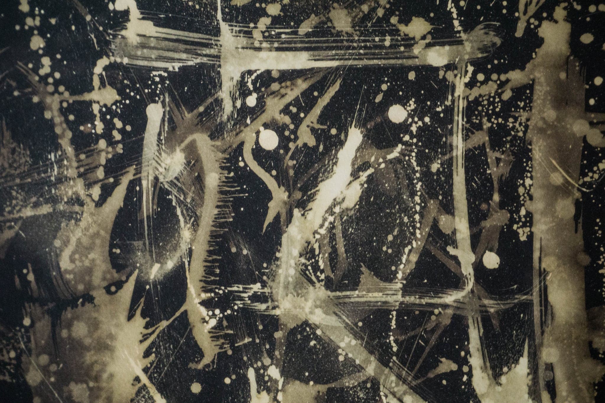 A dark sheet crowded with pale marks and spatter, denser towards the centre.