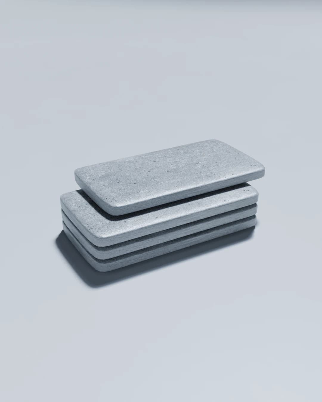 Low concrete table: four stacked slabs with a fifth laid loose across the top, set off-centre