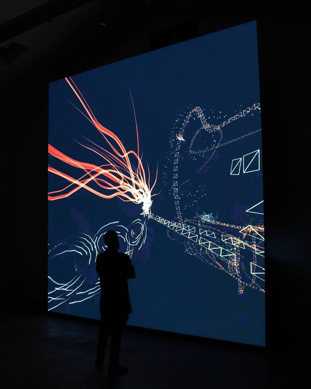 Threads of white and orange light rushing outward across the projection wall