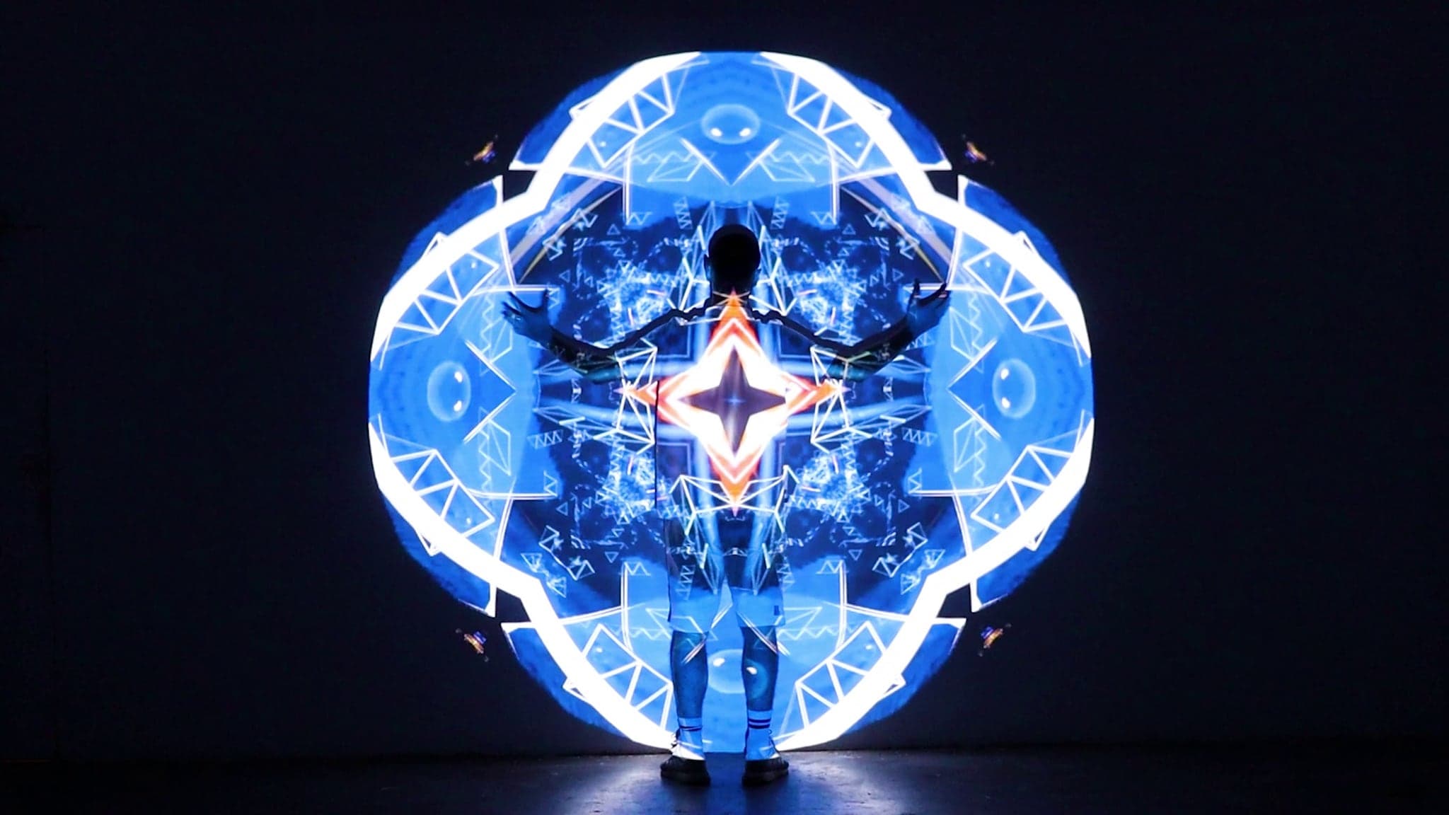 A person standing inside the projection with arms outstretched, a ring of blue light around them
