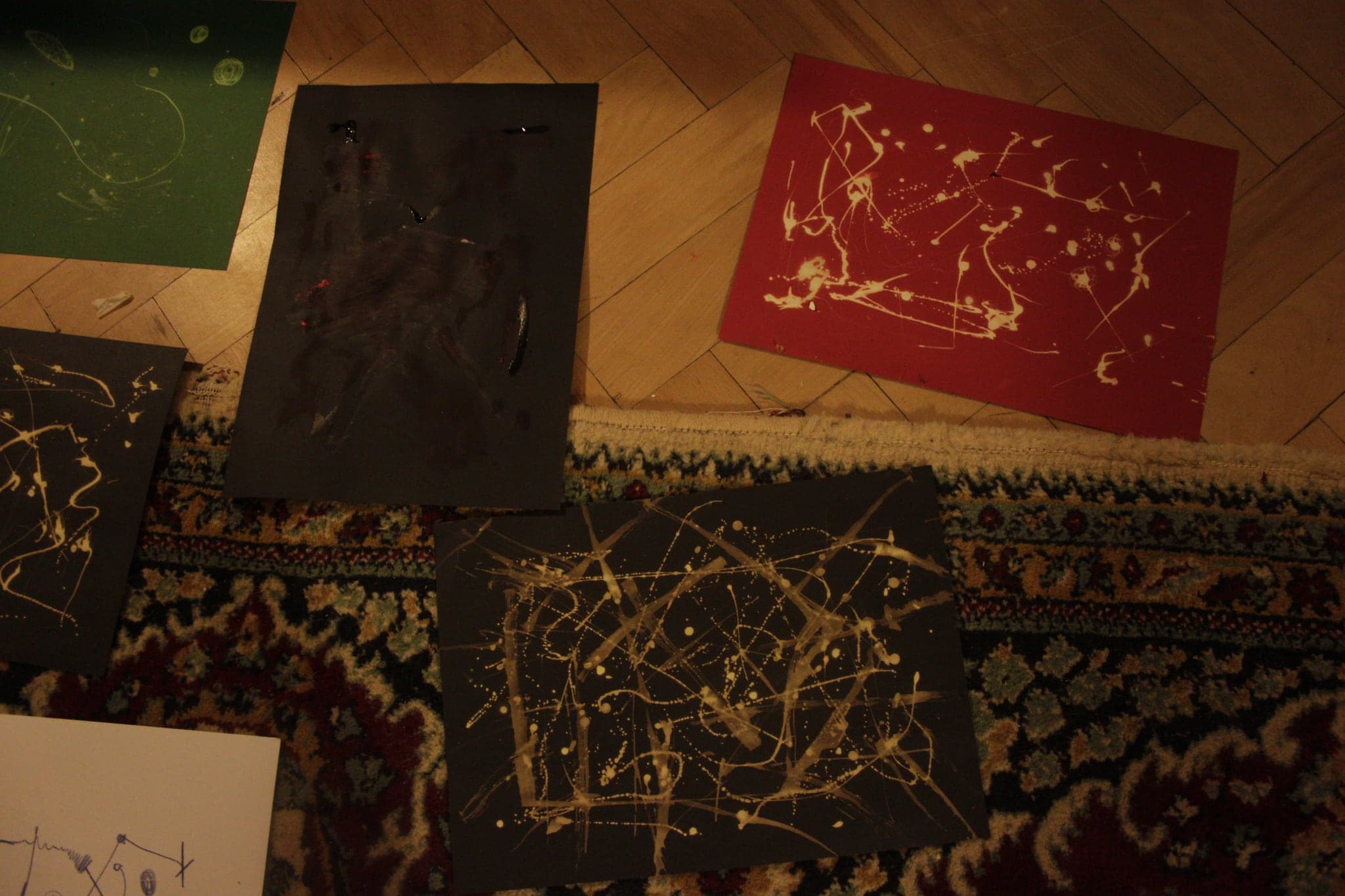 Green and red card and a dark sheet on parquet, each carrying pale scattered marks where chlorine has taken the colour out