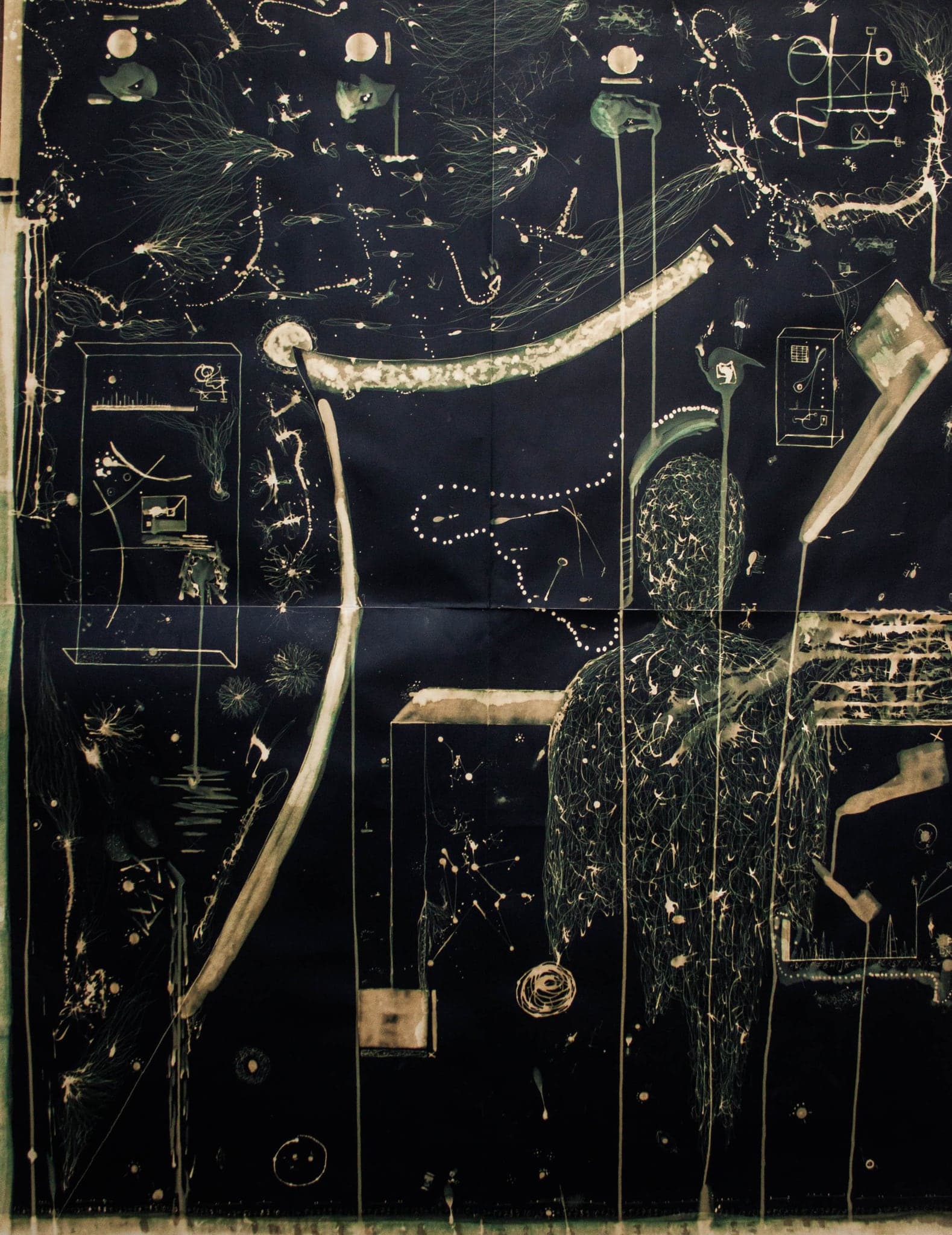 A large fold-creased sheet of dark blue paper drawn in bleach: a standing figure made of fine pale threads, a long curved bow, boxes and scattered dots.