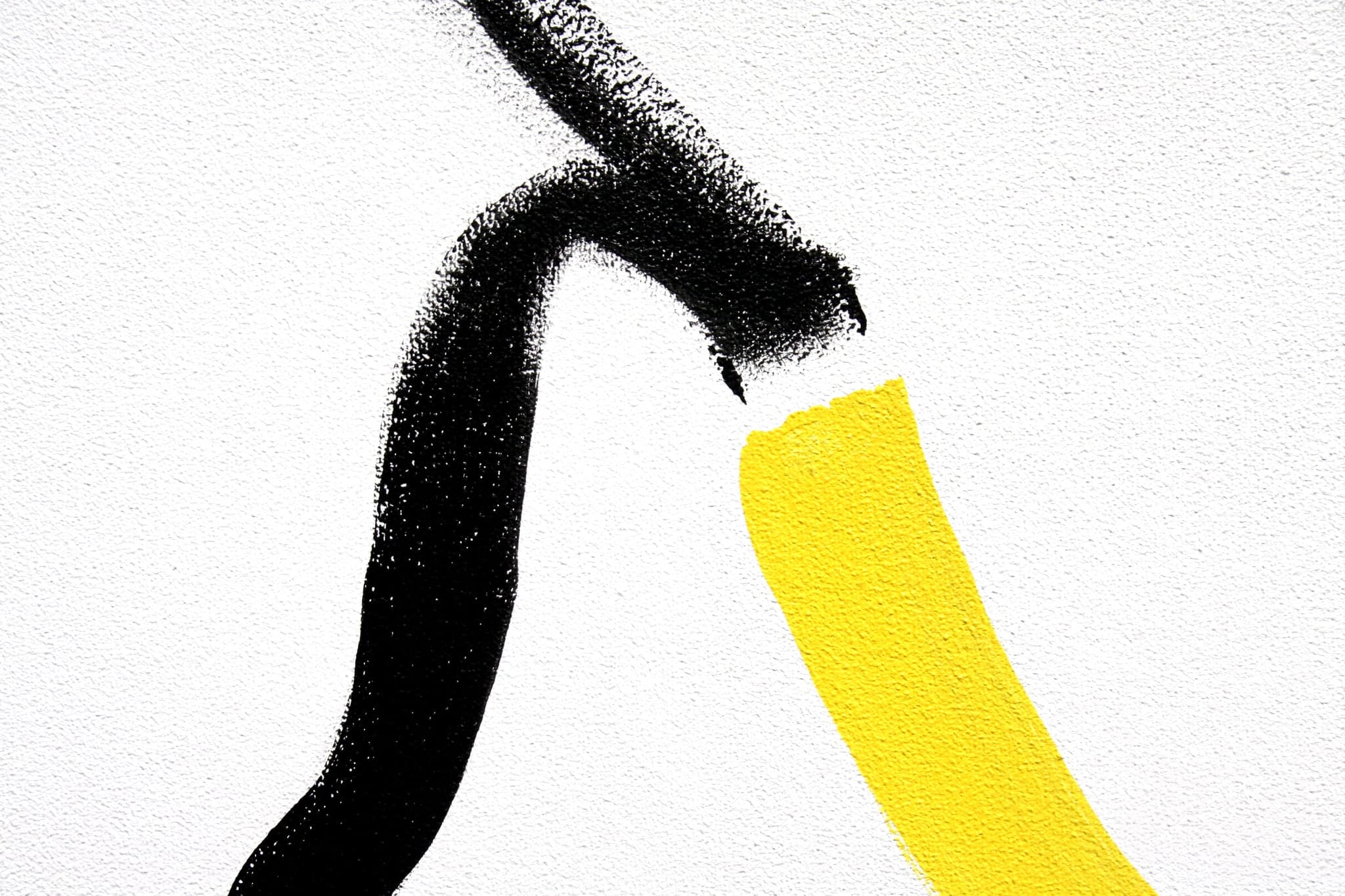 Close view of the surface: one thick black brush stroke meeting a bar of yellow on bare white canvas.