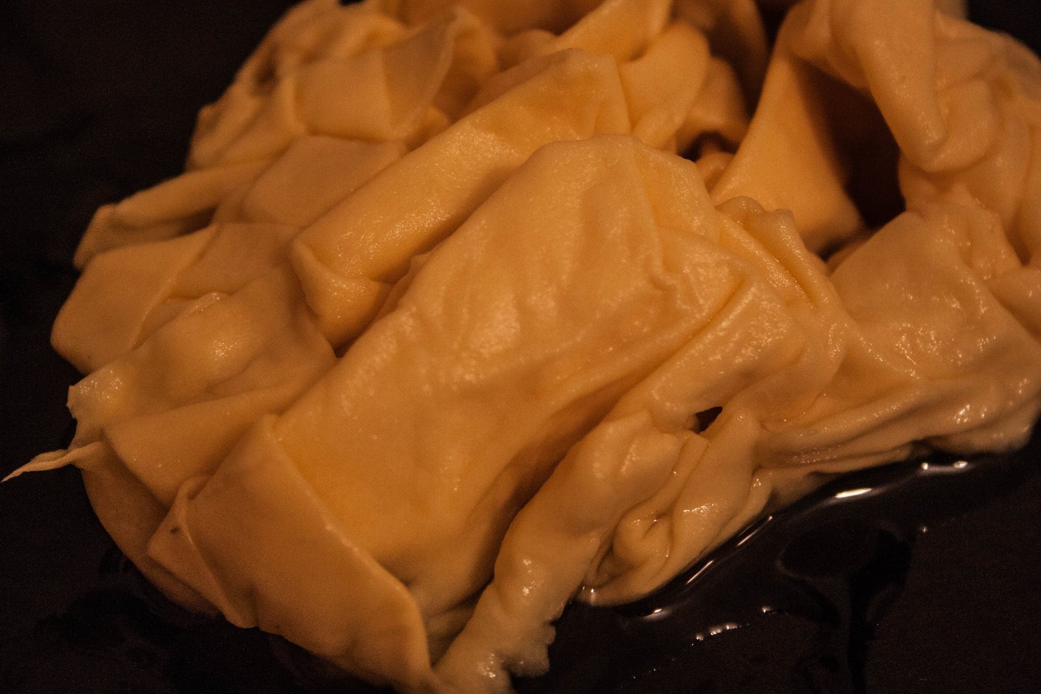 The folded sheet going into something dark, turning ochre where the liquid has reached it.