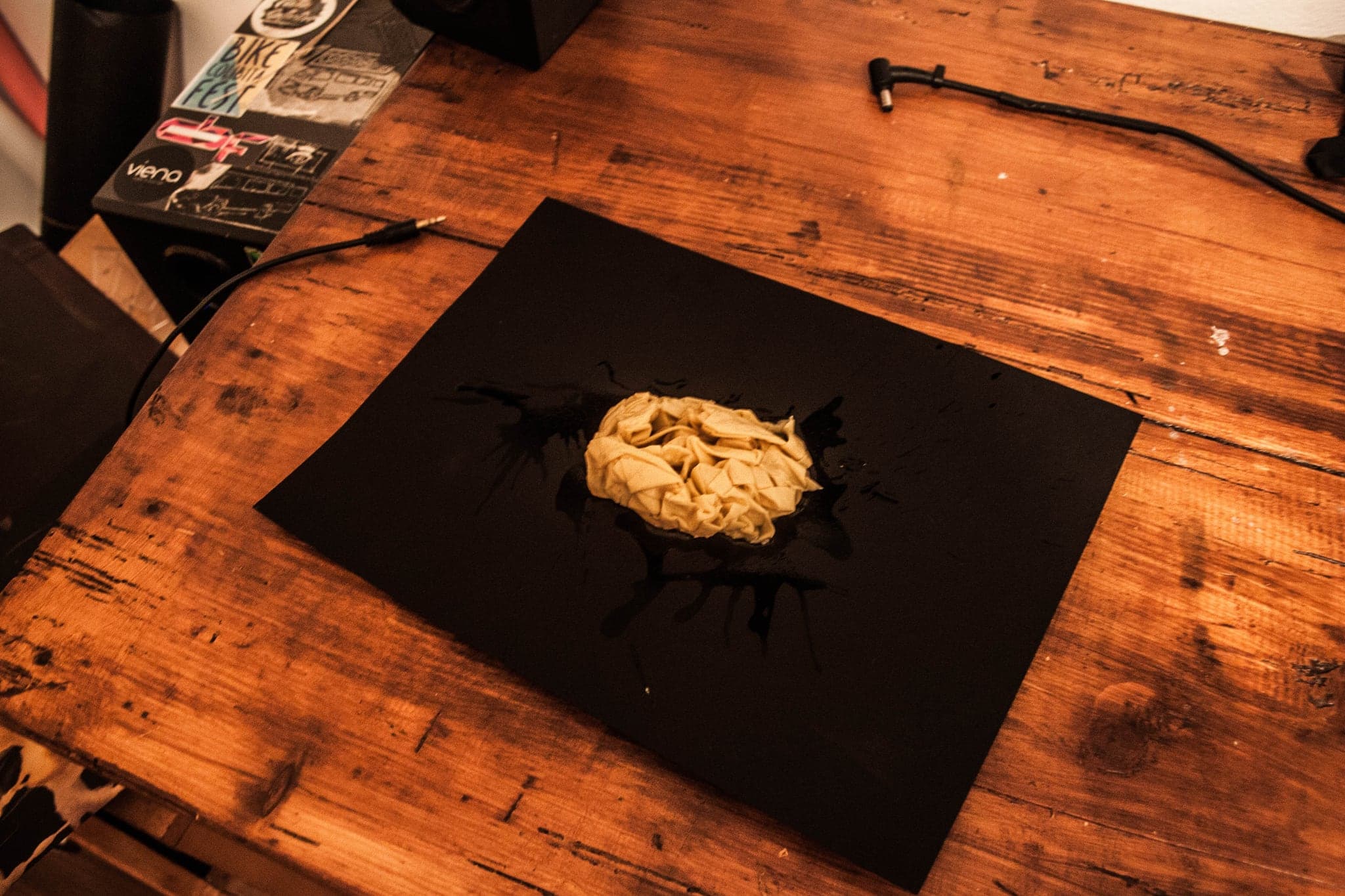 The soaked bundle set down on a black sheet on a wooden workbench, small and crumpled.