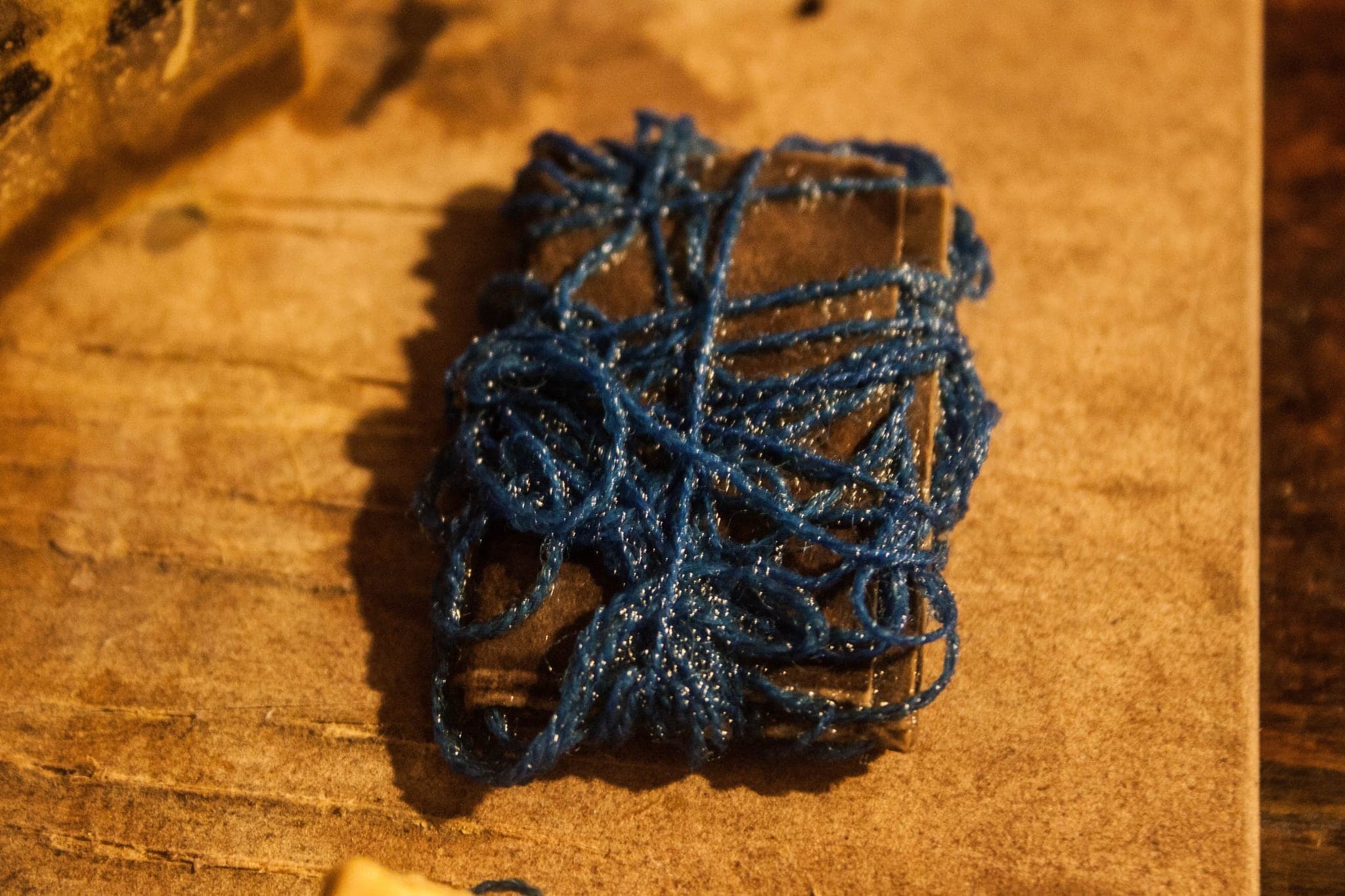 The bundle wrapped tightly in blue thread, sitting on a golden worked surface.