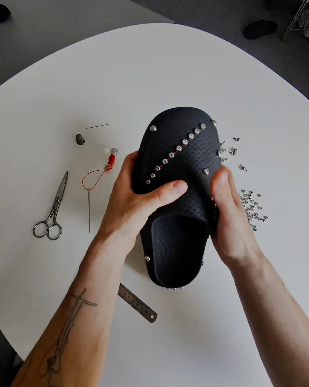 Overhead view of both hands holding the studded shoe up off the white table to check the line