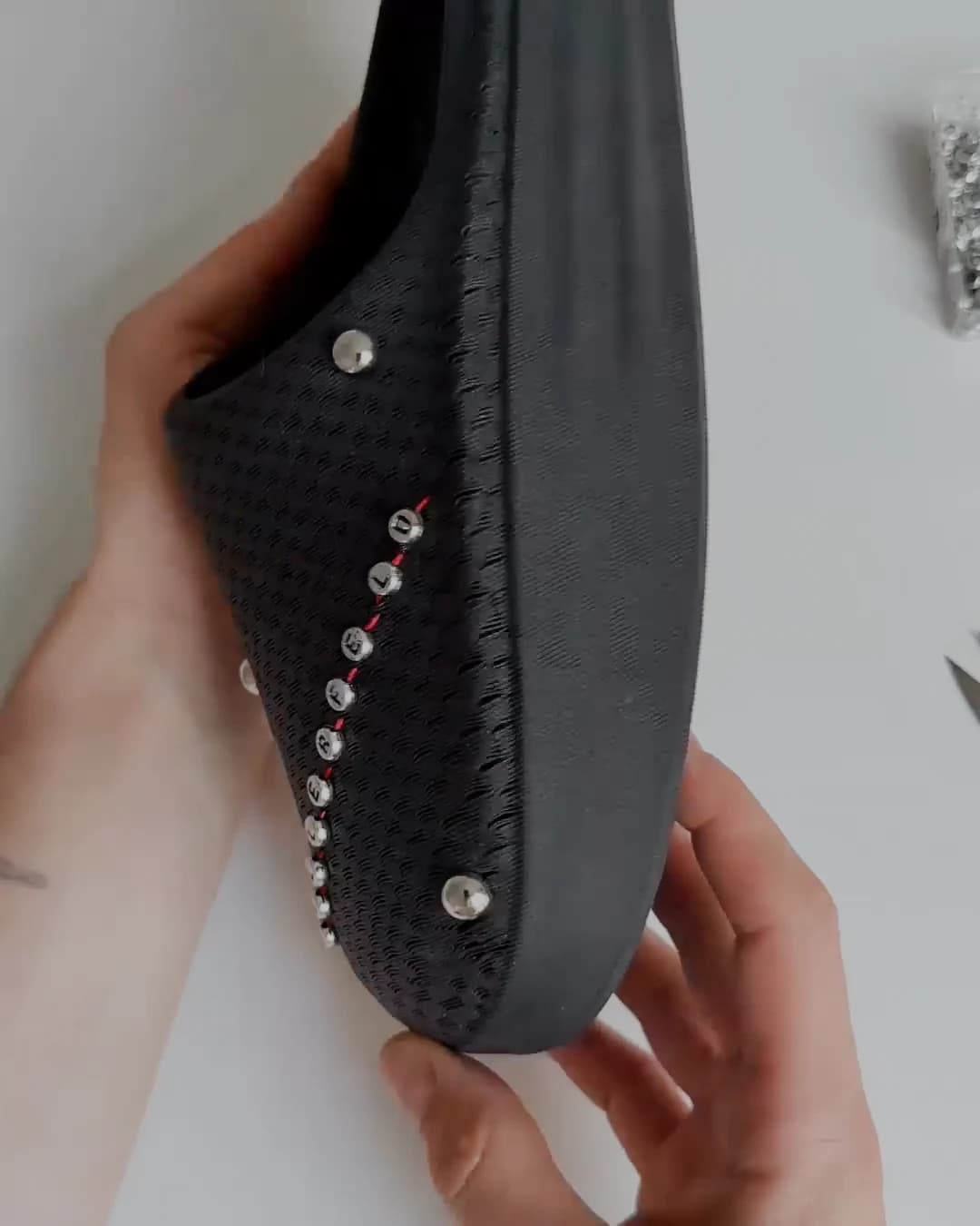 The black shoe on the table with the completed curve of studs running the length of the upper