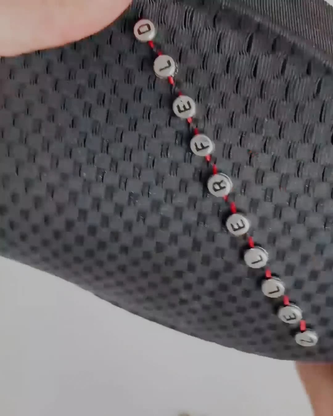 The completed line of beads and studs running the length of the upper, red thread visible between each one