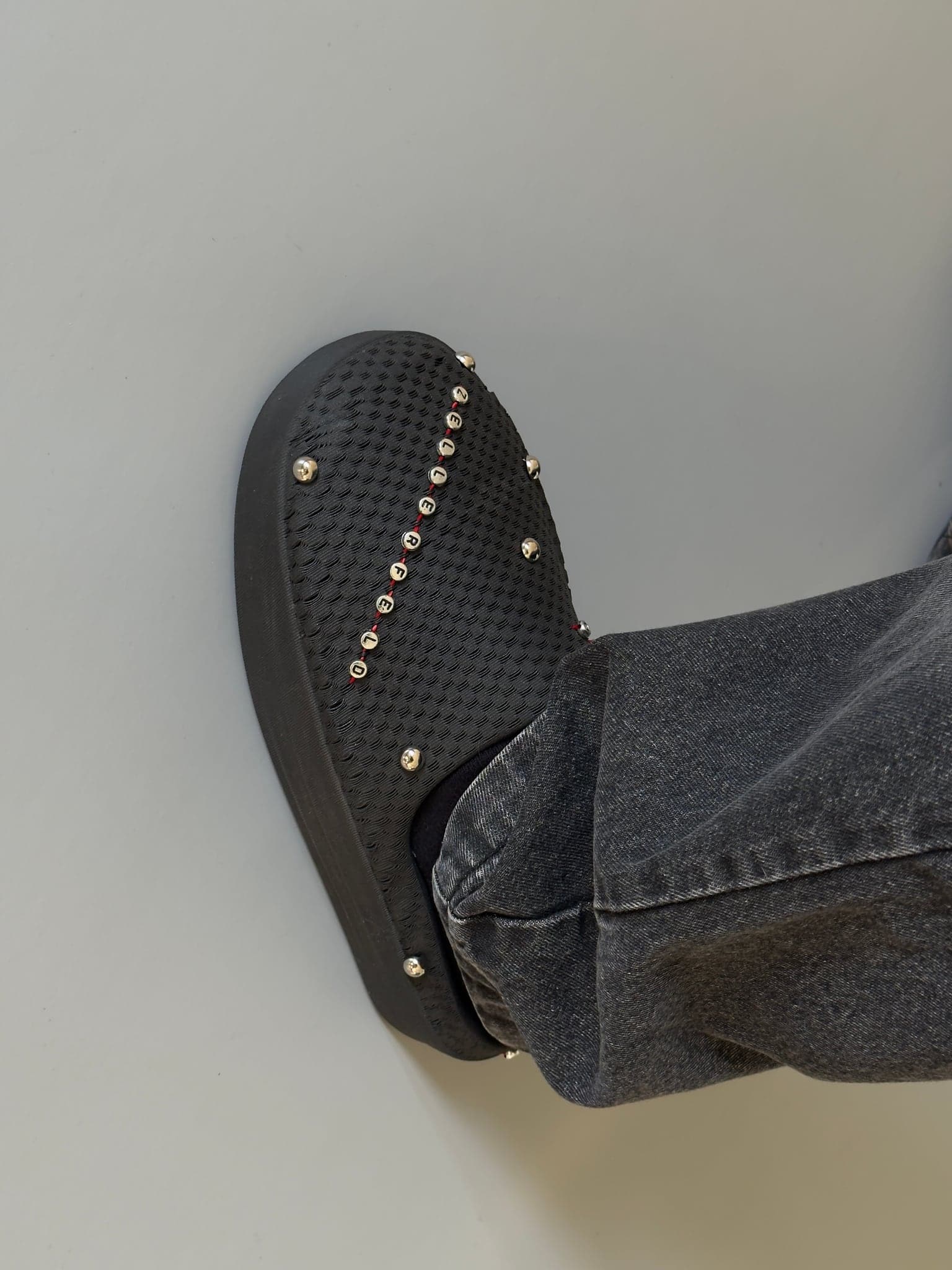 The finished shoe worn with dark denim, the studs picked out against the black printed upper