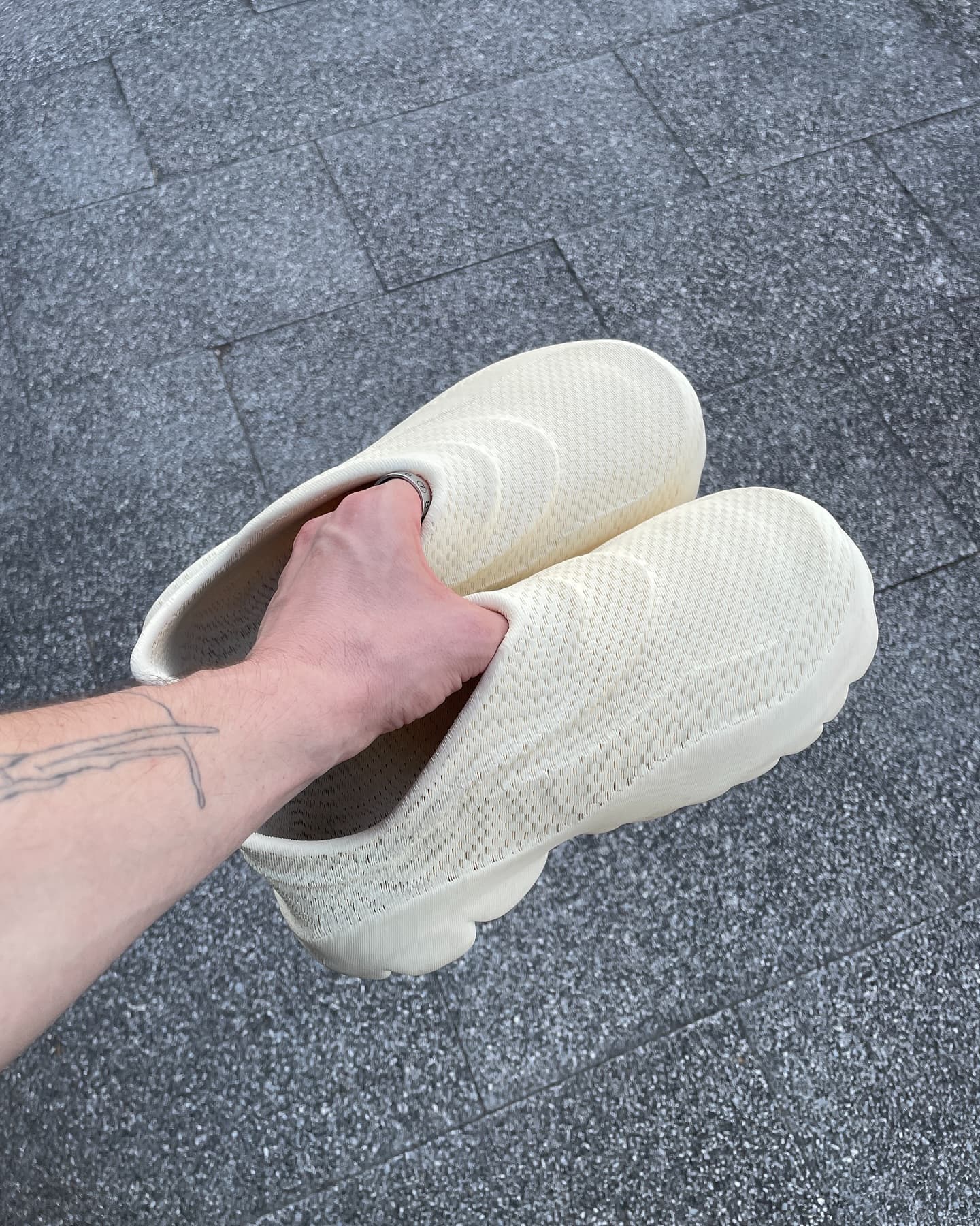 Cream P100 pair held in one hand, showing the perforated one-piece upper
