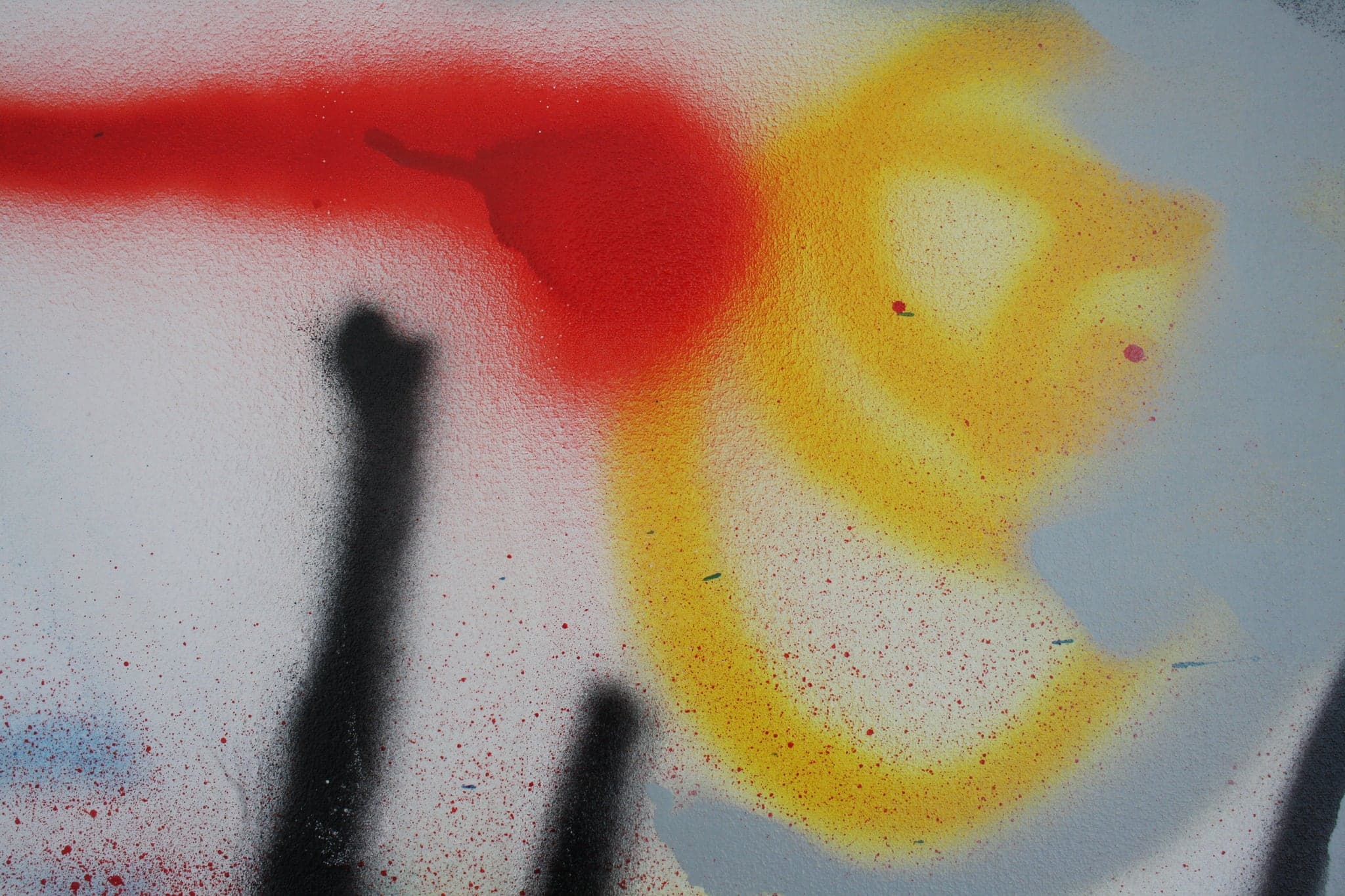 Close view: the red mass where the can was held still, a black stroke entering it and yellow spreading below.