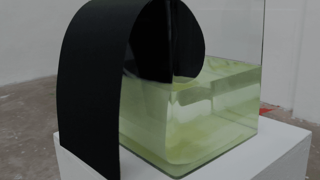 Close view of the arch of black paper filling the frame above the green liquid