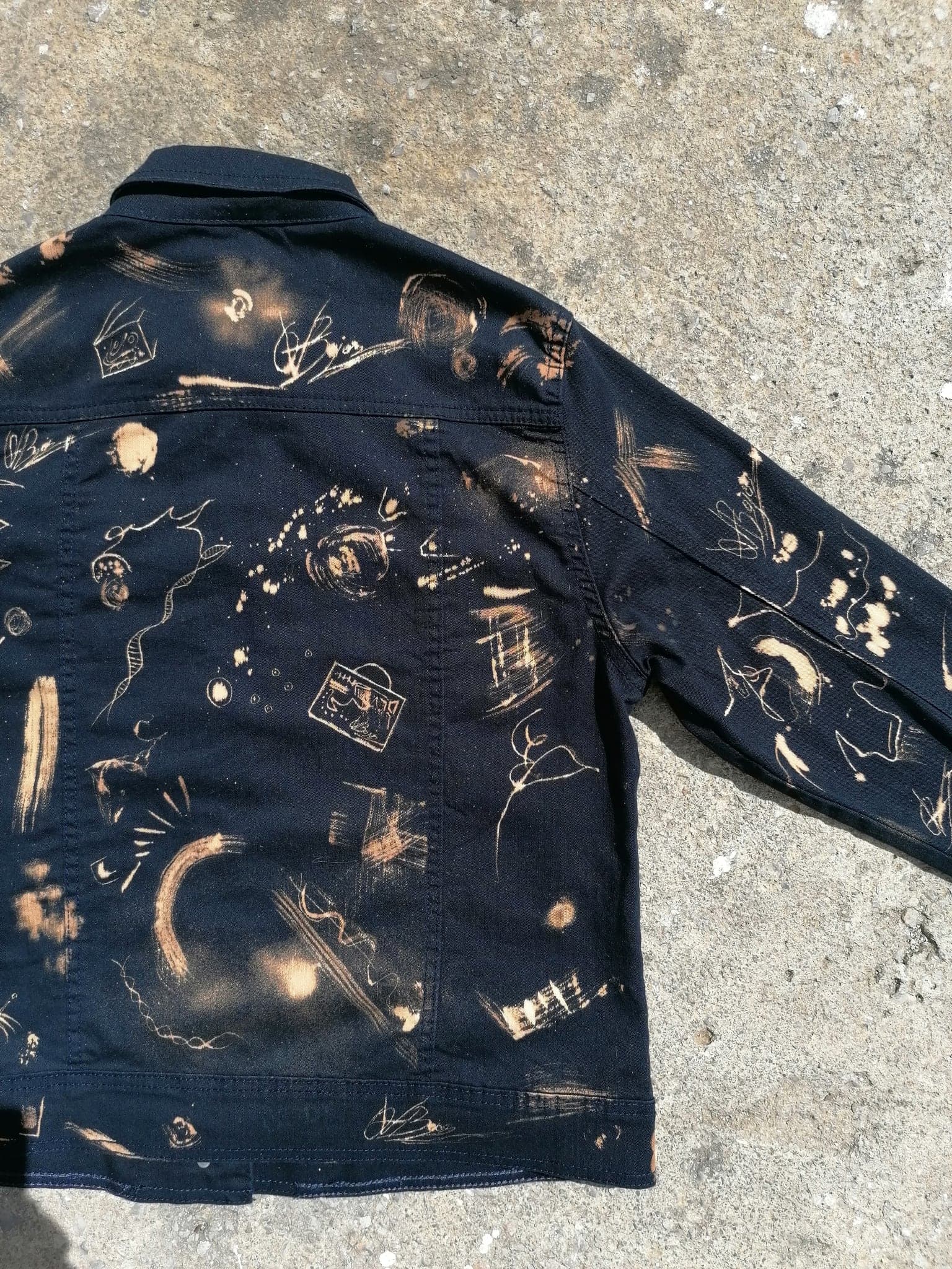 The jacket folded on concrete, the back and one sleeve showing together