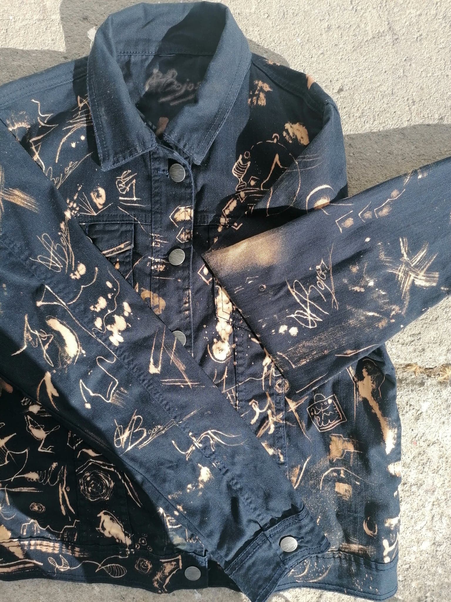 The jacket folded so one arm lies across the body, the marks continuing down the sleeve