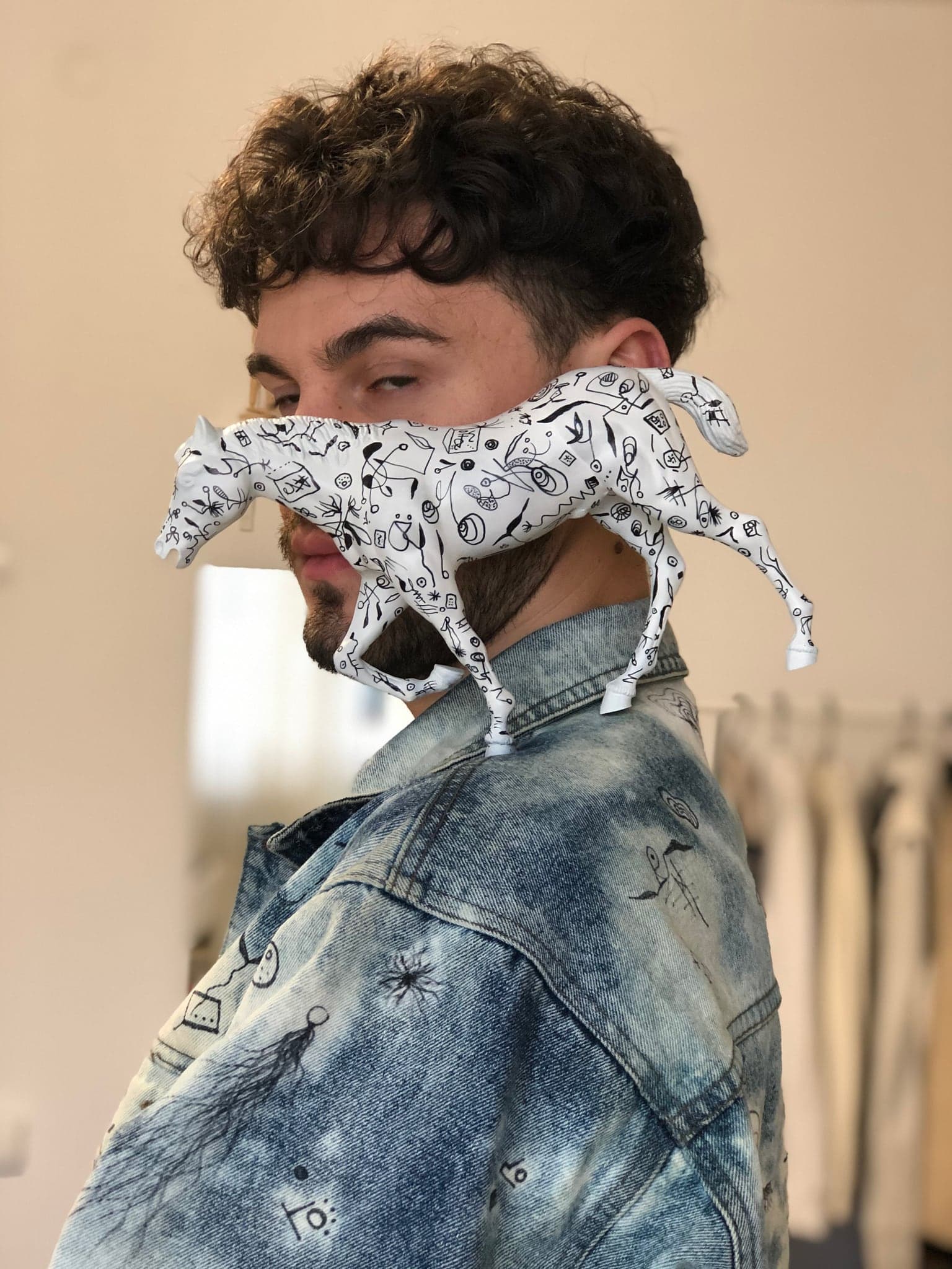 The paper horse held up in profile so that it crosses the artist's eyes