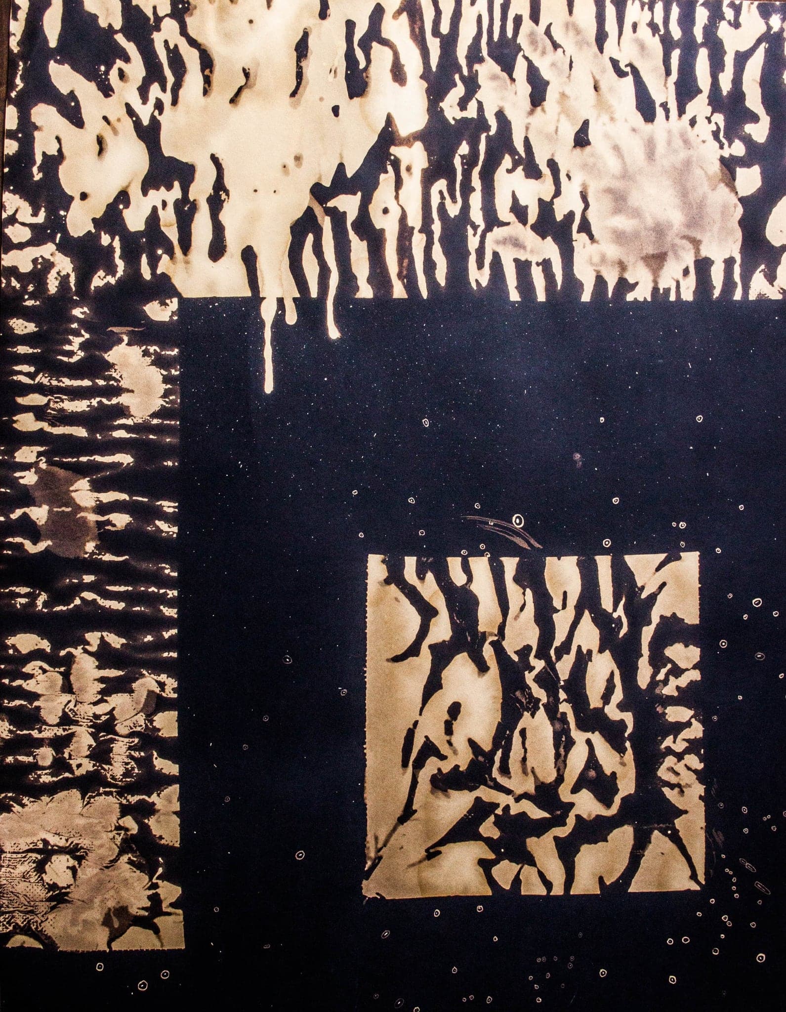 Large fields of black paper bleached down to cream, breaking into dark islands and drips, with two rectangular zones left untouched and dark.