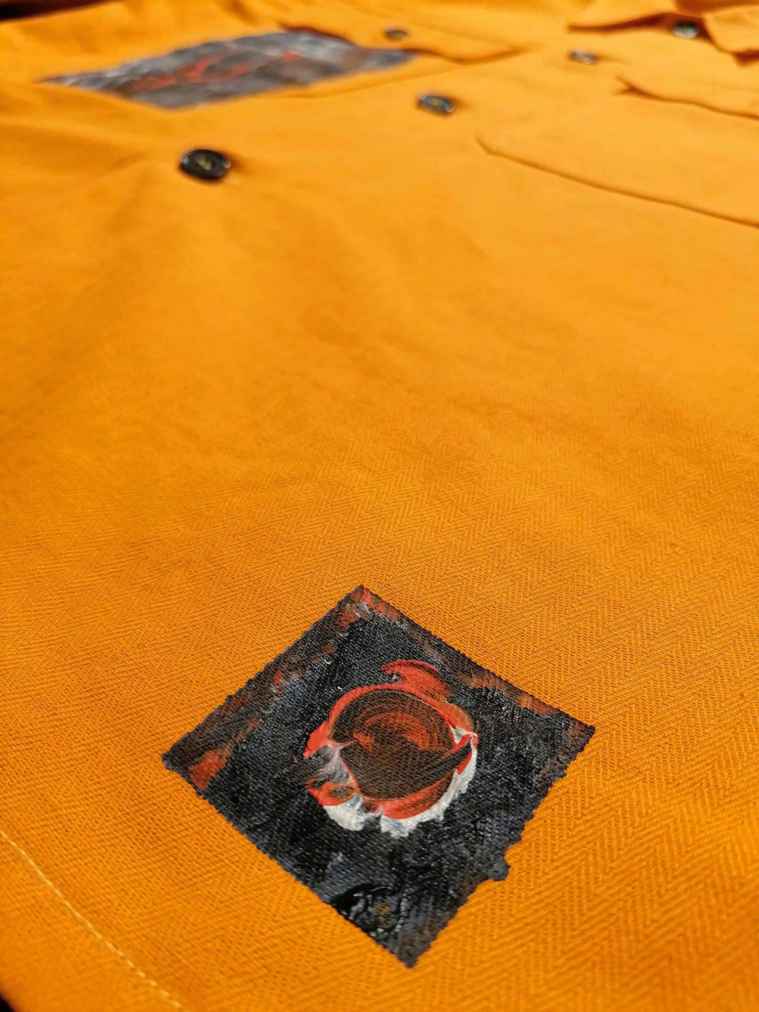 A small diamond of painted canvas sewn to the sleeve, raw edges showing