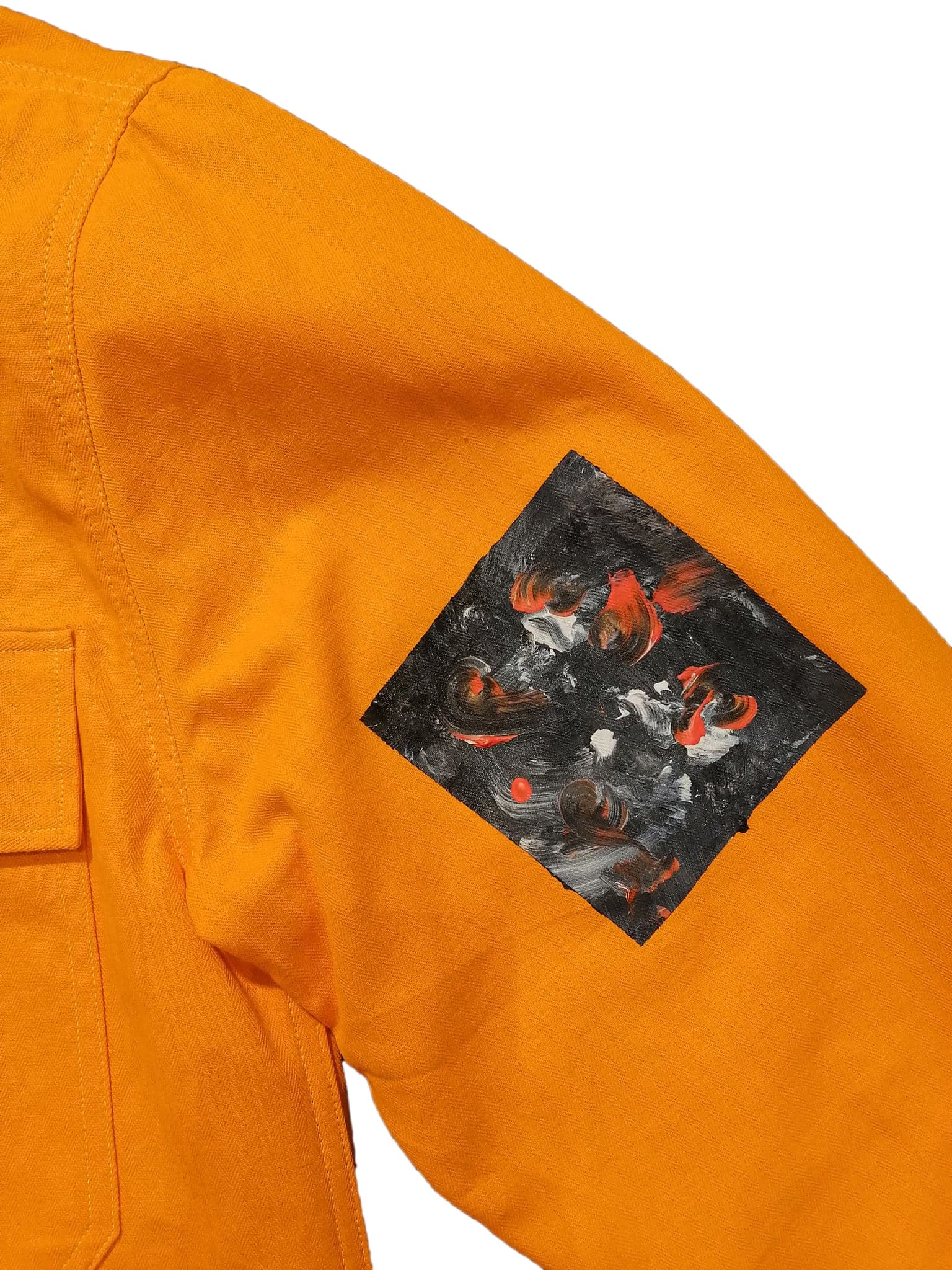 A rectangular painted patch on the other sleeve, the stitching visible around it
