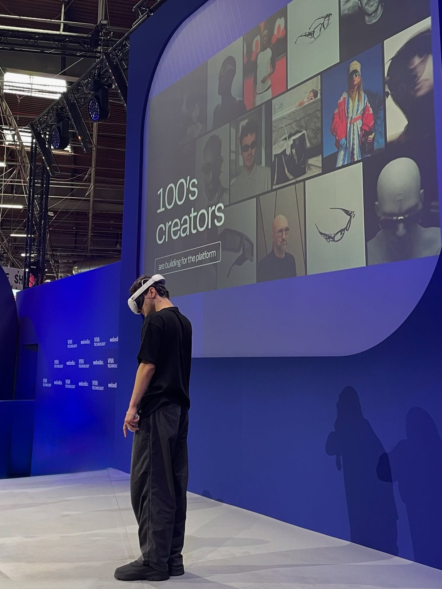 The VivaTech hall, a large screen reading 100s of creators, a figure walking past
