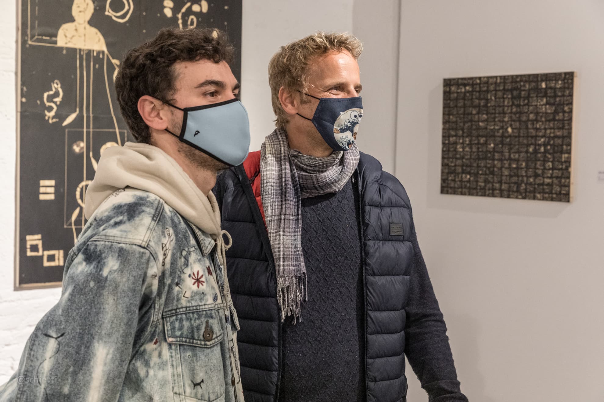 Two men talking at the opening, the nearer one wearing the cloud-bleached denim jacket over a hoodie