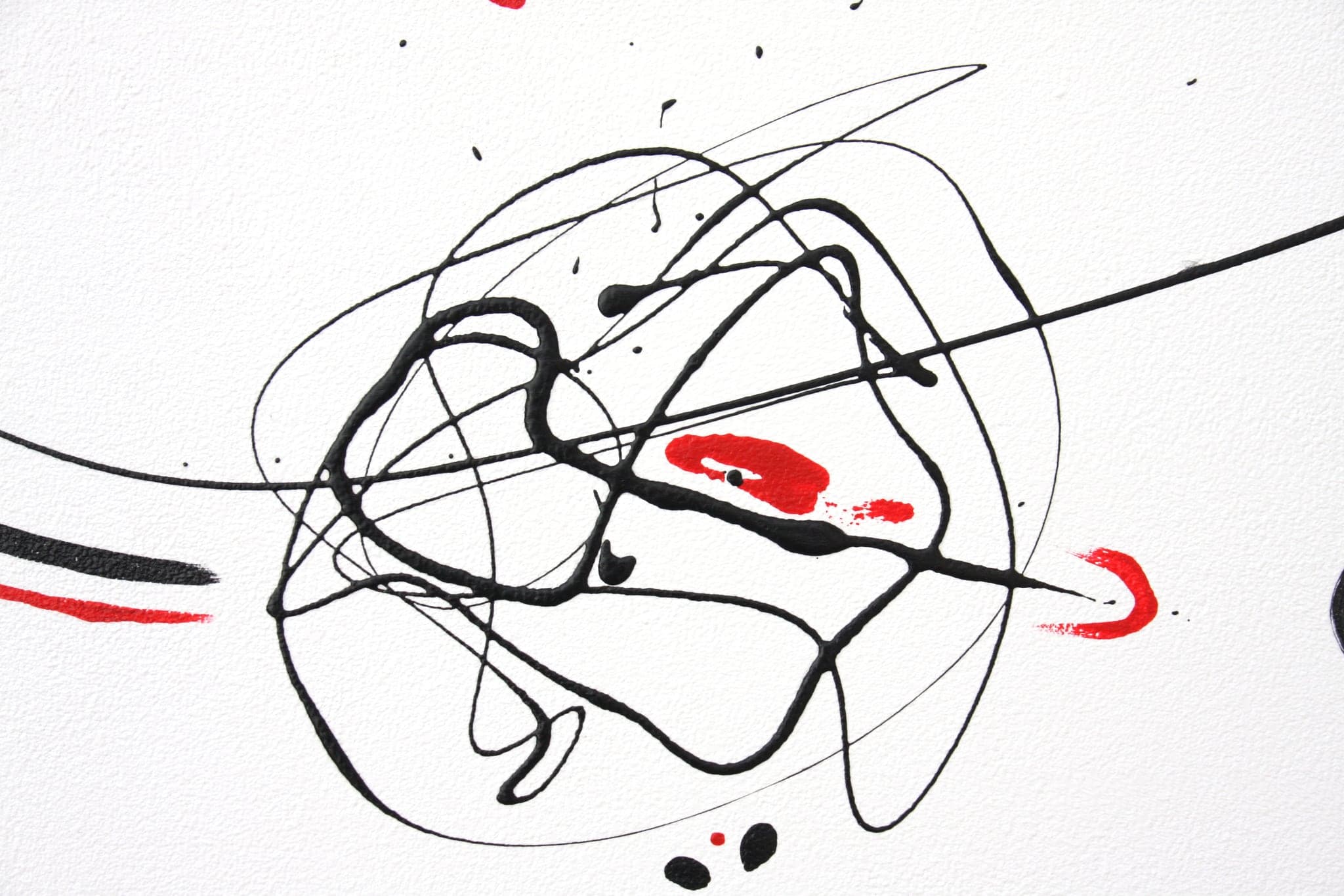 Close view of a tangle of black loops crossing a long black line, with red marks lying under it